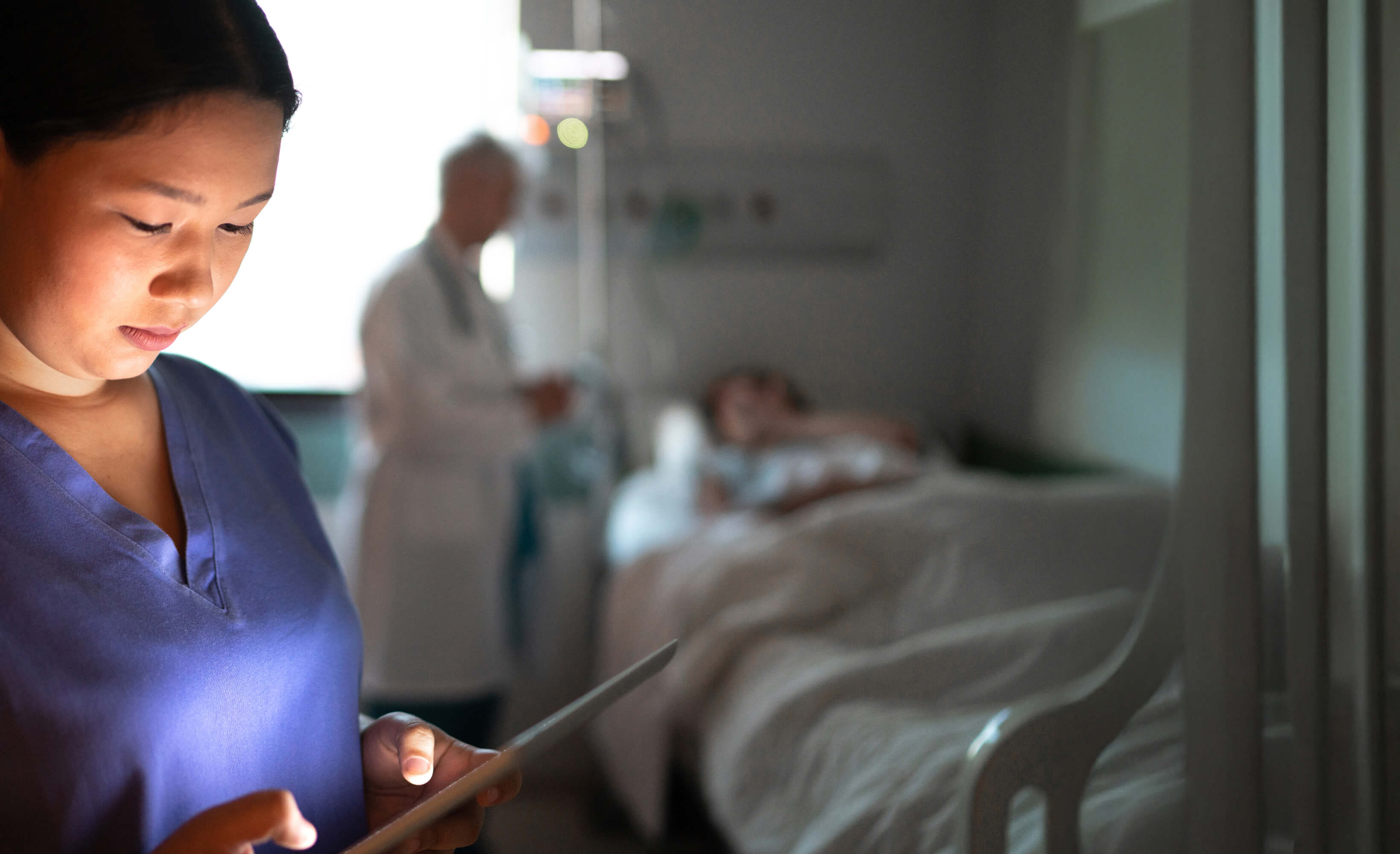 a woman holding a tablet in a hospital room